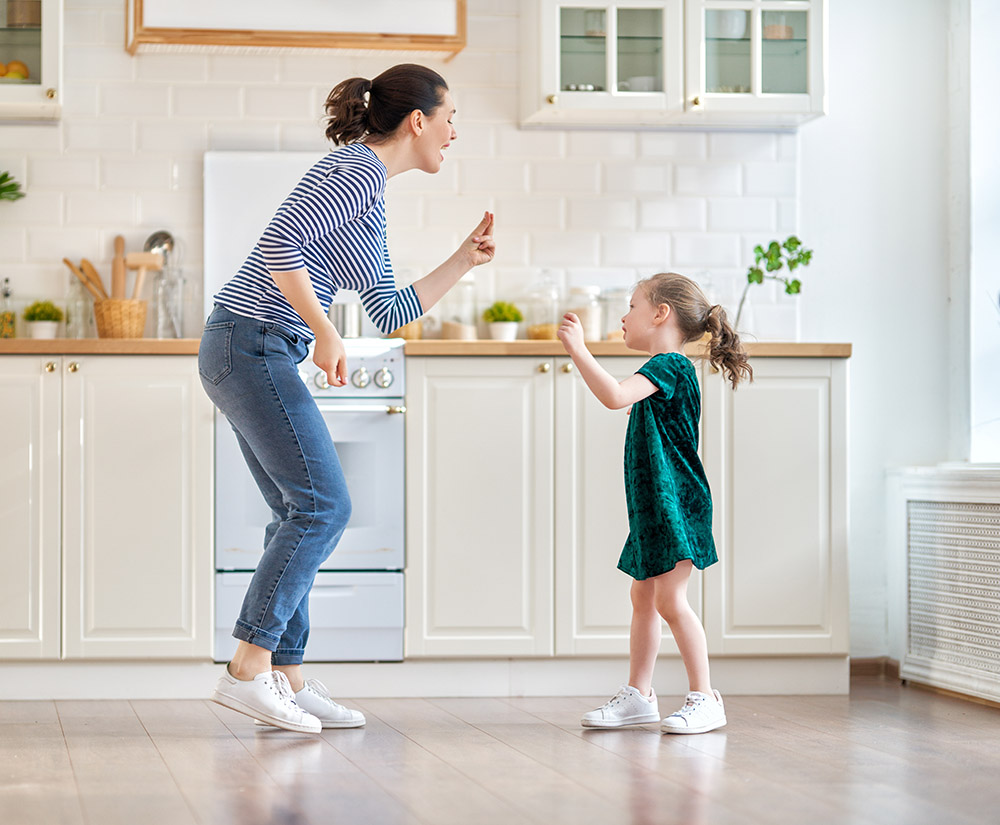 Mother and daughter dancing in the kitchen with home audio system